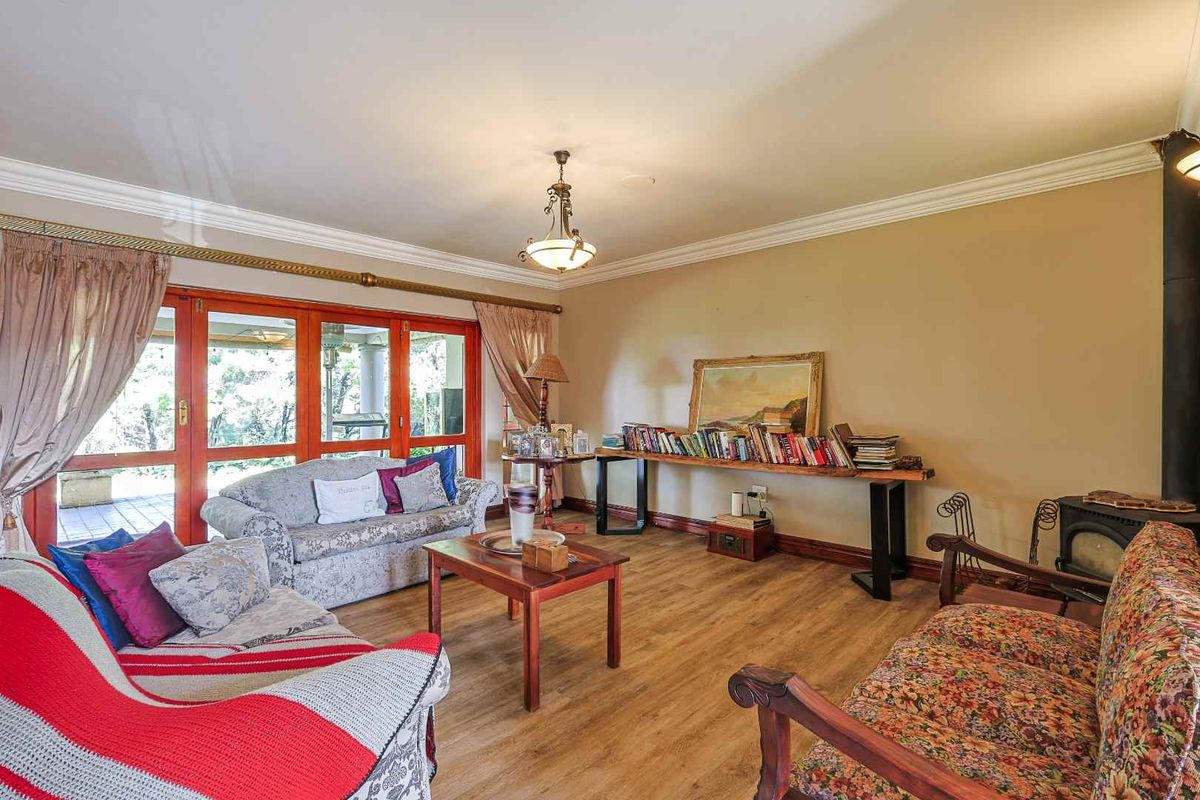 Spacious living room featuring laminate flooring, crown molding, and a wood-burning fireplace, with direct access to the outdoor patio through timber-framed sliding doors.