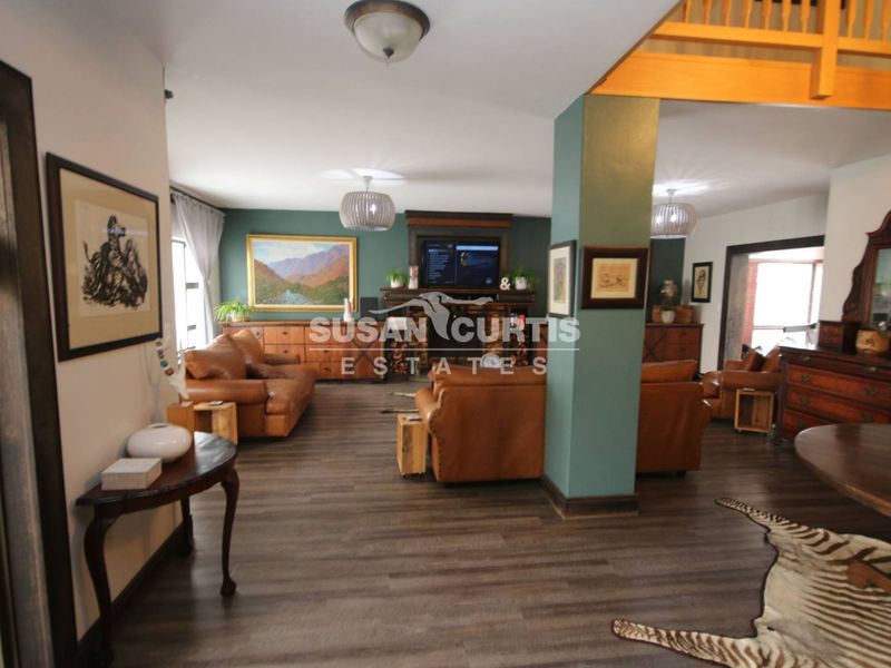 Spacious open-plan living area featuring dark laminate flooring, a central fireplace, and exposed timber architectural elements, creating a warm and inviting atmosphere.