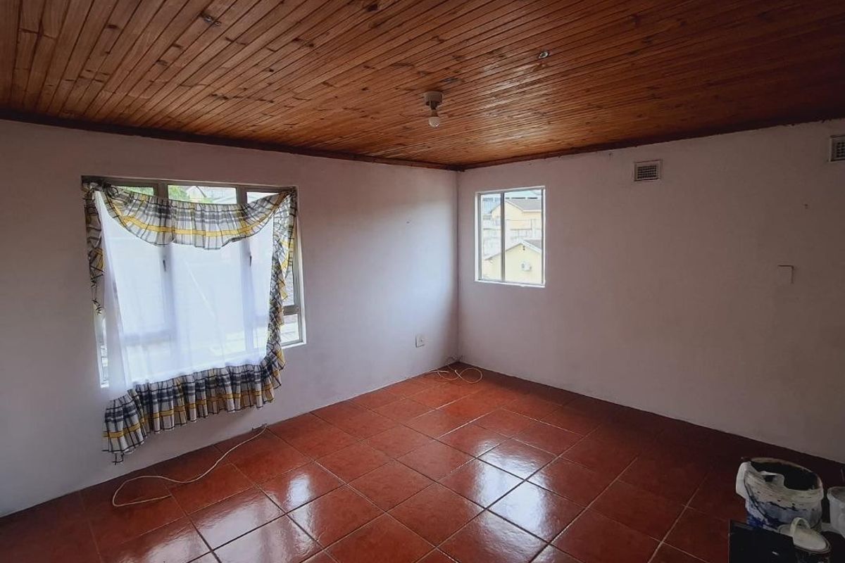 An empty bedroom featuring a timber-clad ceiling and terracotta-style ceramic floor tiles, offering a blank canvas for renovation.