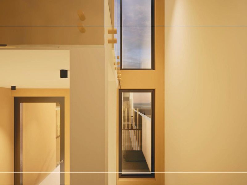 A modern, minimalist hallway featuring double-height windows that provide ample natural light and a clean, architectural aesthetic.