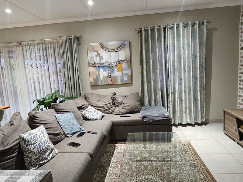 A well-maintained living room featuring an exposed brick accent wall, tiled flooring, and large sliding doors providing access to the outdoor area.