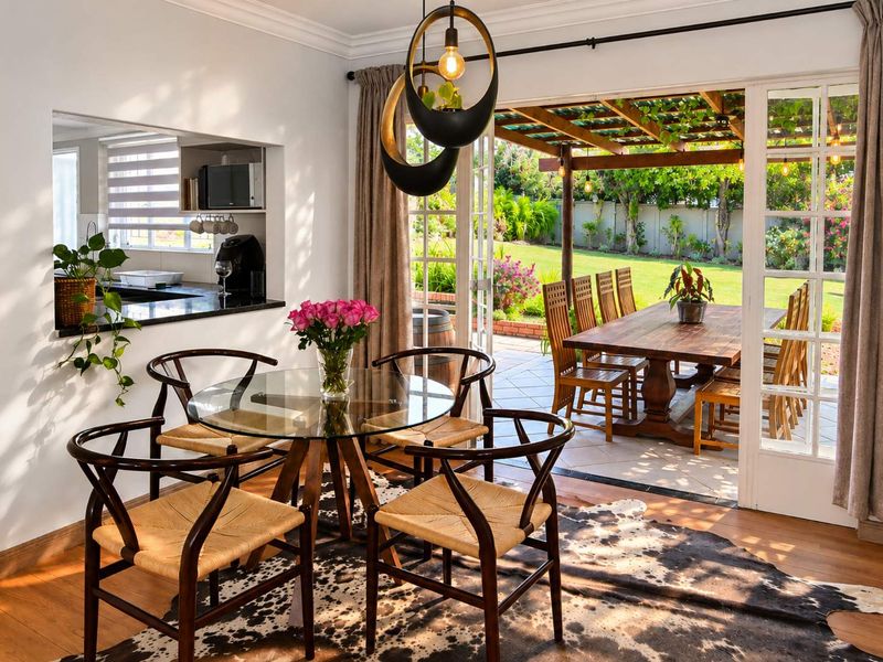Open plan dining area featuring a kitchen pass-through window and seamless flow to a covered outdoor patio and garden.