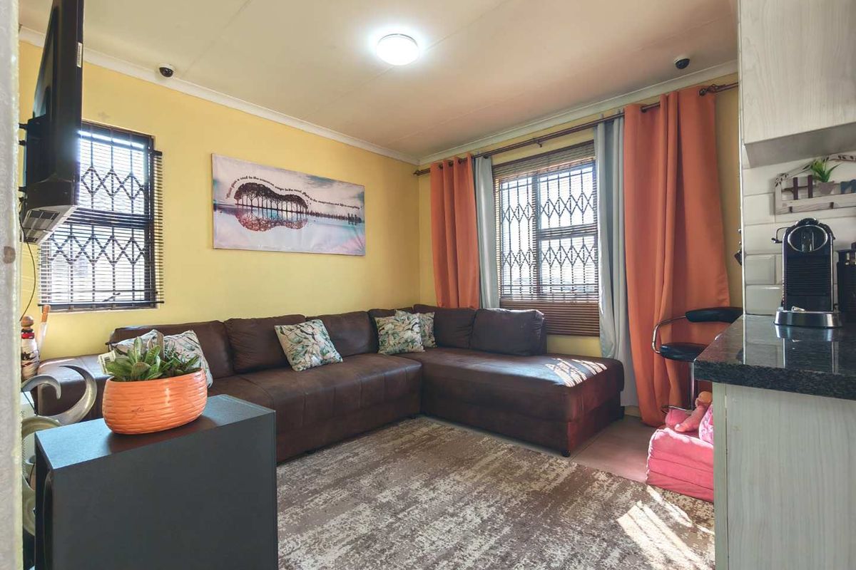 A cozy living room featuring security bars on windows and neutral wall finishes, providing a functional and comfortable space for relaxation.