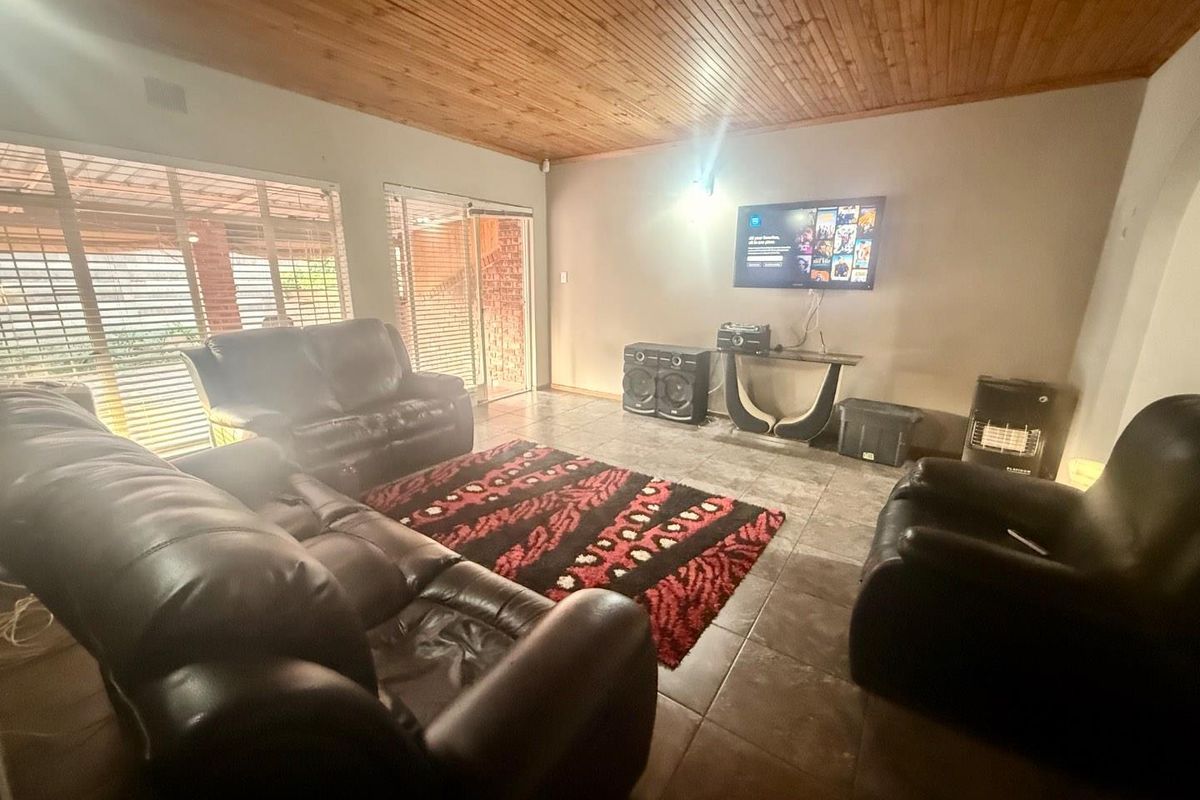 Spacious living room featuring tiled flooring, a timber-clad ceiling, and large windows providing natural light and access to the outdoor area.