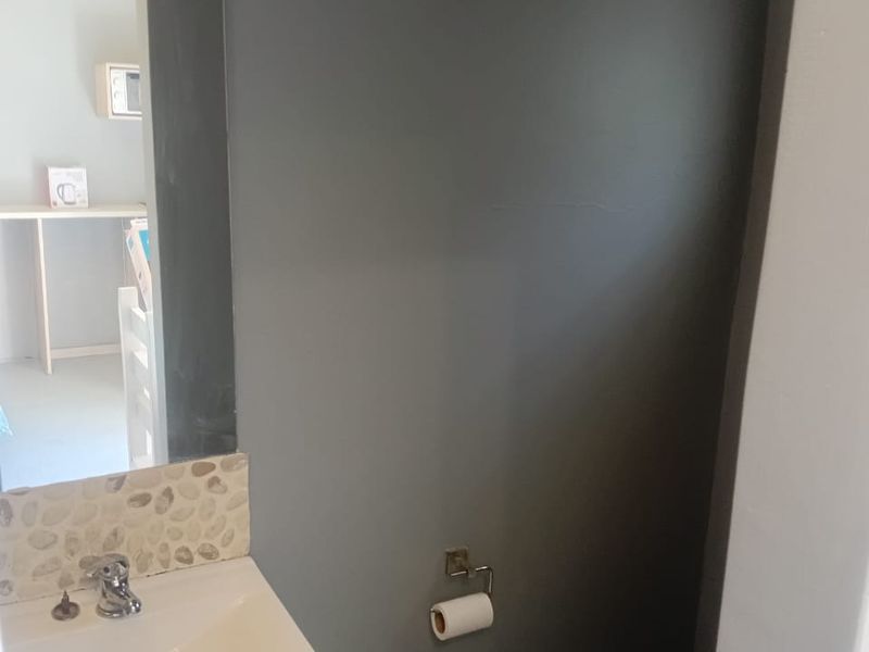 A compact bathroom featuring a wall-mounted basin with a pebble mosaic splashback, a chrome mixer tap, and a toilet.