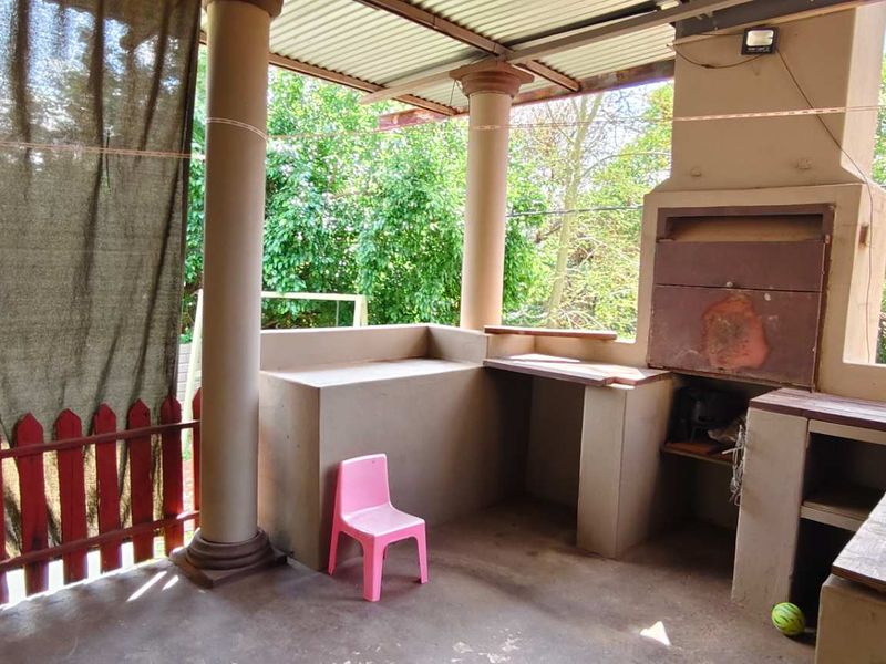Covered patio area featuring a built-in braai, concrete prep counters, and structural columns, offering a functional space for outdoor entertaining.