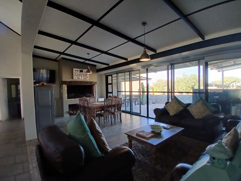 Spacious open-plan living and dining area featuring a built-in fireplace, exposed beam ceiling, and large sliding glass doors leading to the outdoor patio.