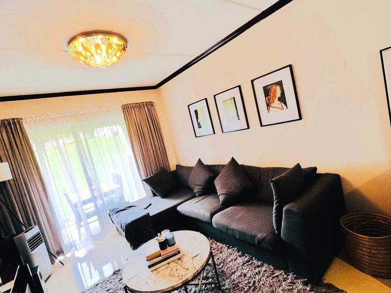A well-lit living room featuring tiled flooring and a large sliding glass door providing access to the outdoor area.