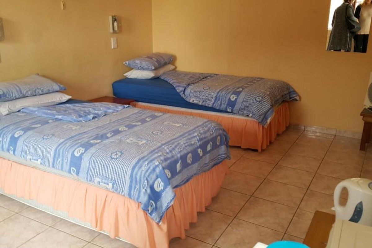A bedroom featuring tiled flooring and wall-mounted lighting fixtures, currently configured with two single beds.