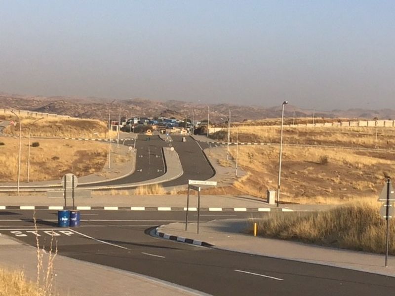 A view of the paved road infrastructure and surrounding vacant land area, featuring established street lighting and curbing.