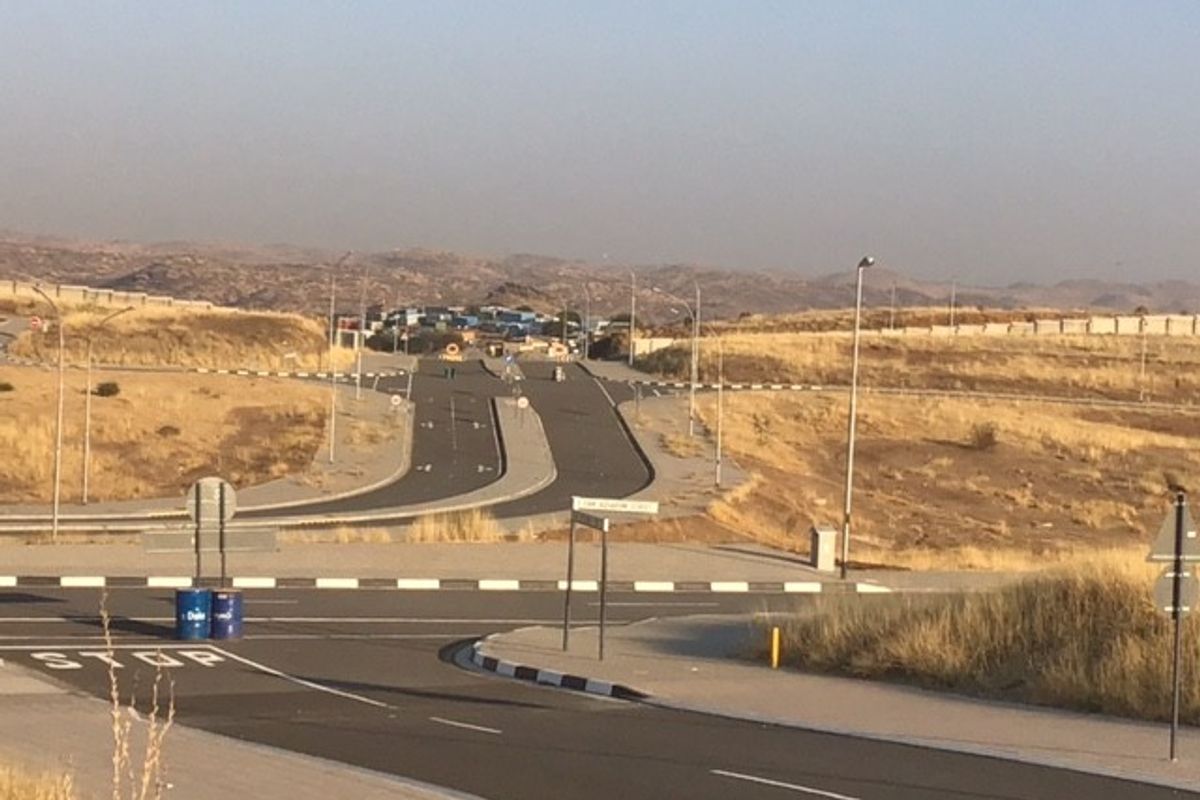 A view of the paved road infrastructure and surrounding vacant land area, featuring established street lighting and curbing.