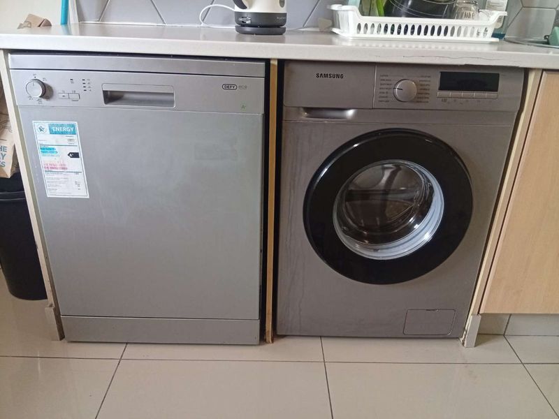 A functional laundry area featuring tiled flooring, a laminate countertop, and integrated dishwasher and washing machine units.