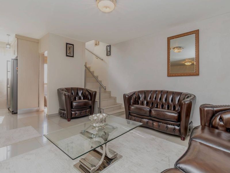 A well-maintained living room featuring tiled flooring and a staircase with a modern metal handrail, creating an open and functional living space.