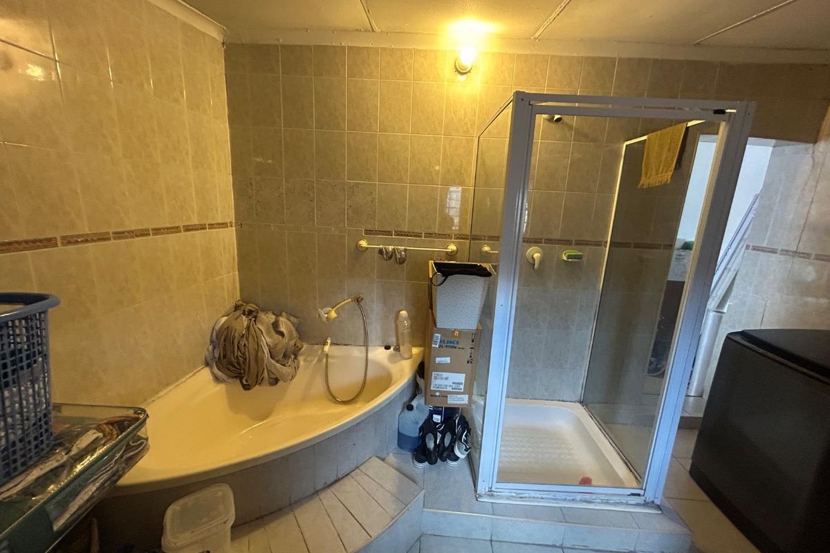 A dated bathroom featuring a corner bathtub, a separate glass-enclosed shower, and tiled walls and flooring.