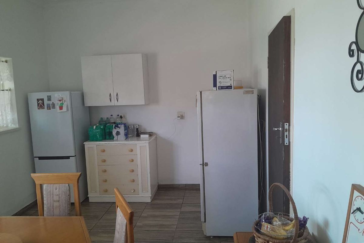 A functional kitchen area featuring tiled flooring, wall-mounted cabinetry, and space for multiple refrigeration units.