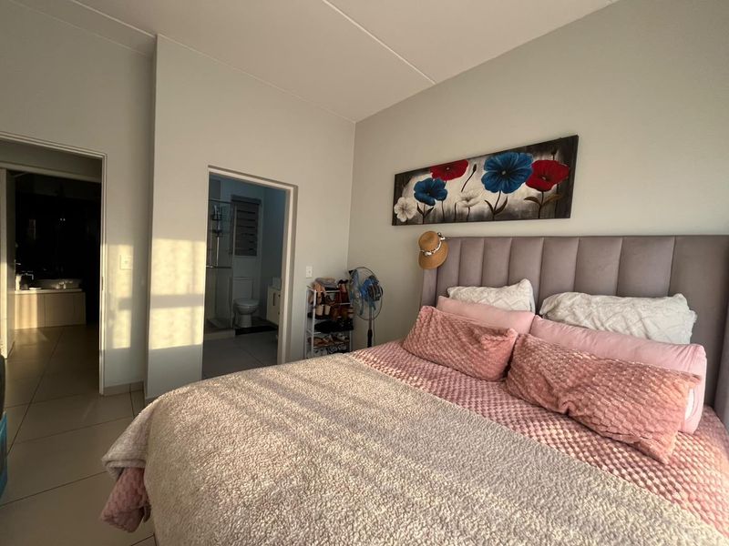 A well-maintained bedroom featuring neutral wall tones, tiled flooring, and direct access to an en-suite bathroom.