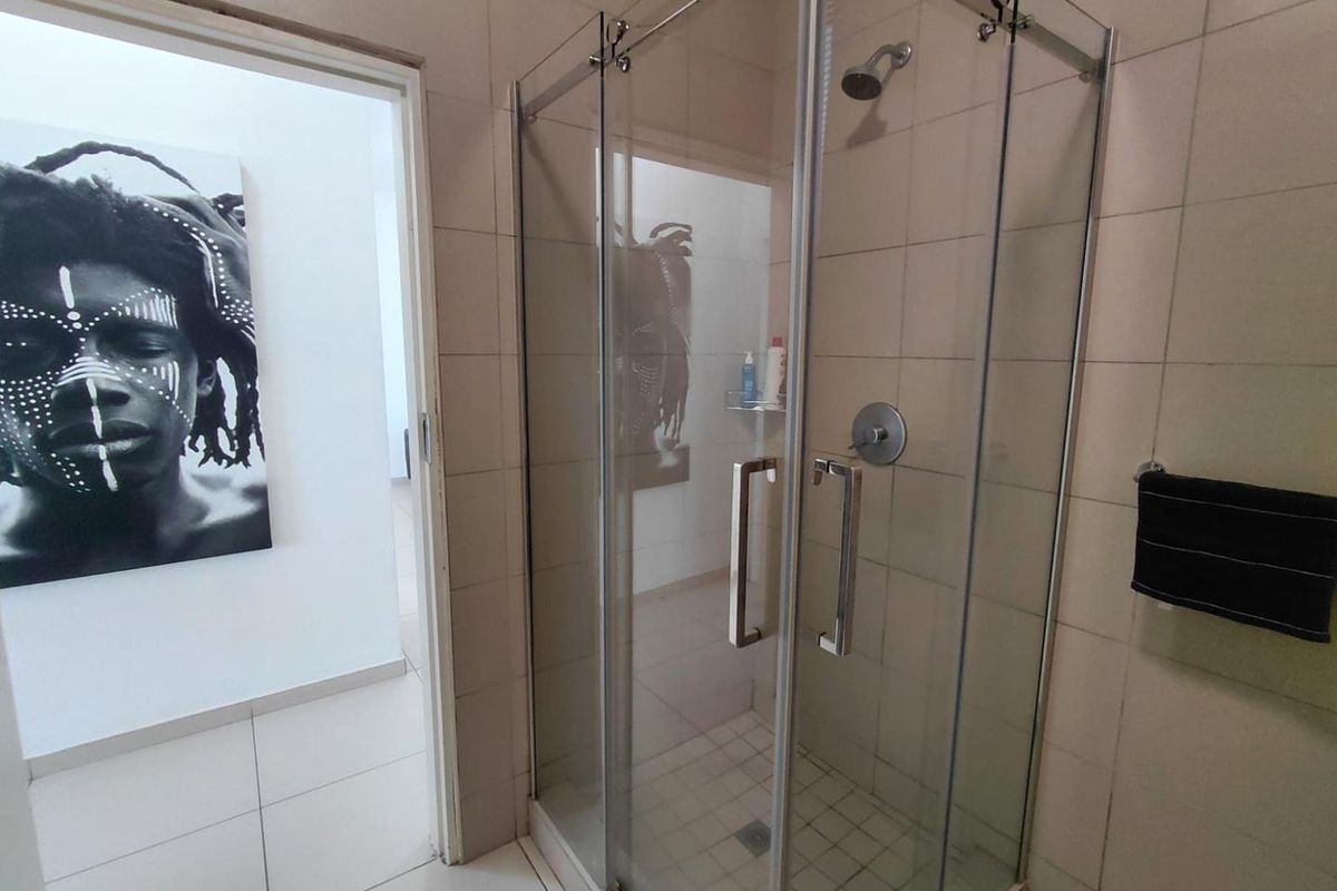 A functional bathroom featuring a glass-enclosed shower with tiled walls and flooring, providing a clean and practical space.
