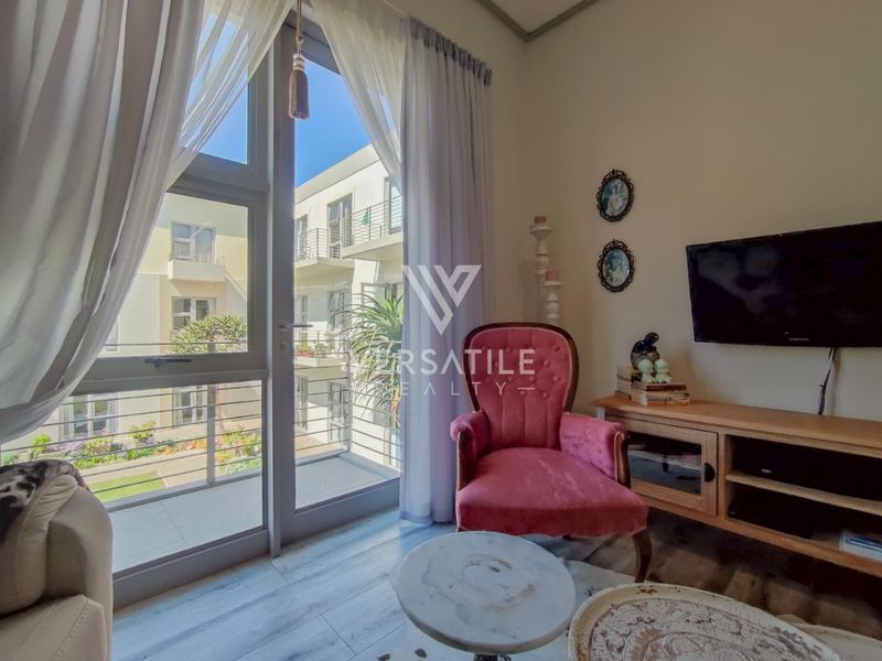 A bright living room featuring laminate flooring and a large sliding glass door providing access to a private balcony.