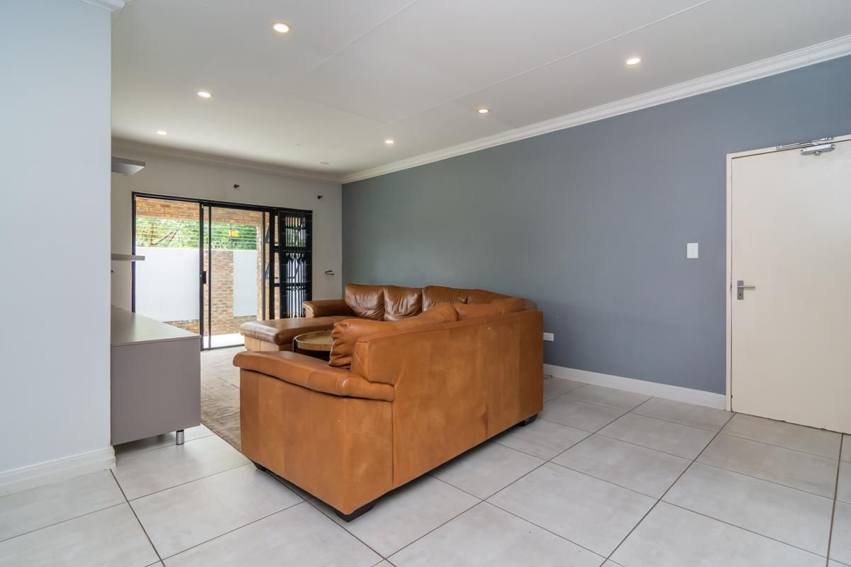 A spacious living area featuring neutral floor tiles, recessed downlighting, and sliding glass doors that provide access to an outdoor patio space.