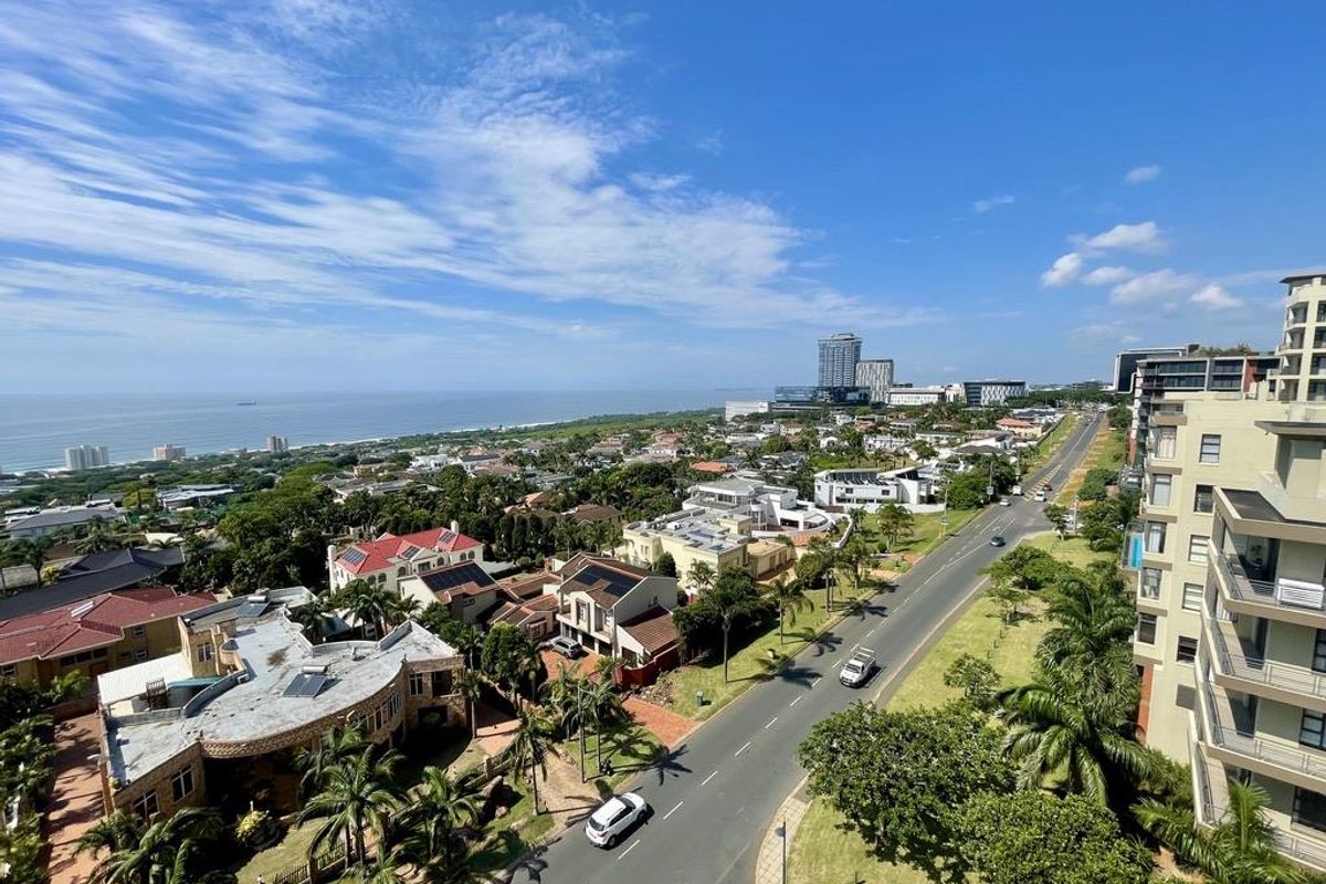 Elevated aerial view overlooking the coastal neighbourhood, surrounding residential properties, and the ocean horizon.