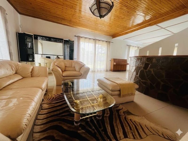 Spacious living room featuring a distinctive timber-clad vaulted ceiling, stone-clad feature wall, and large sliding glass doors providing natural light.