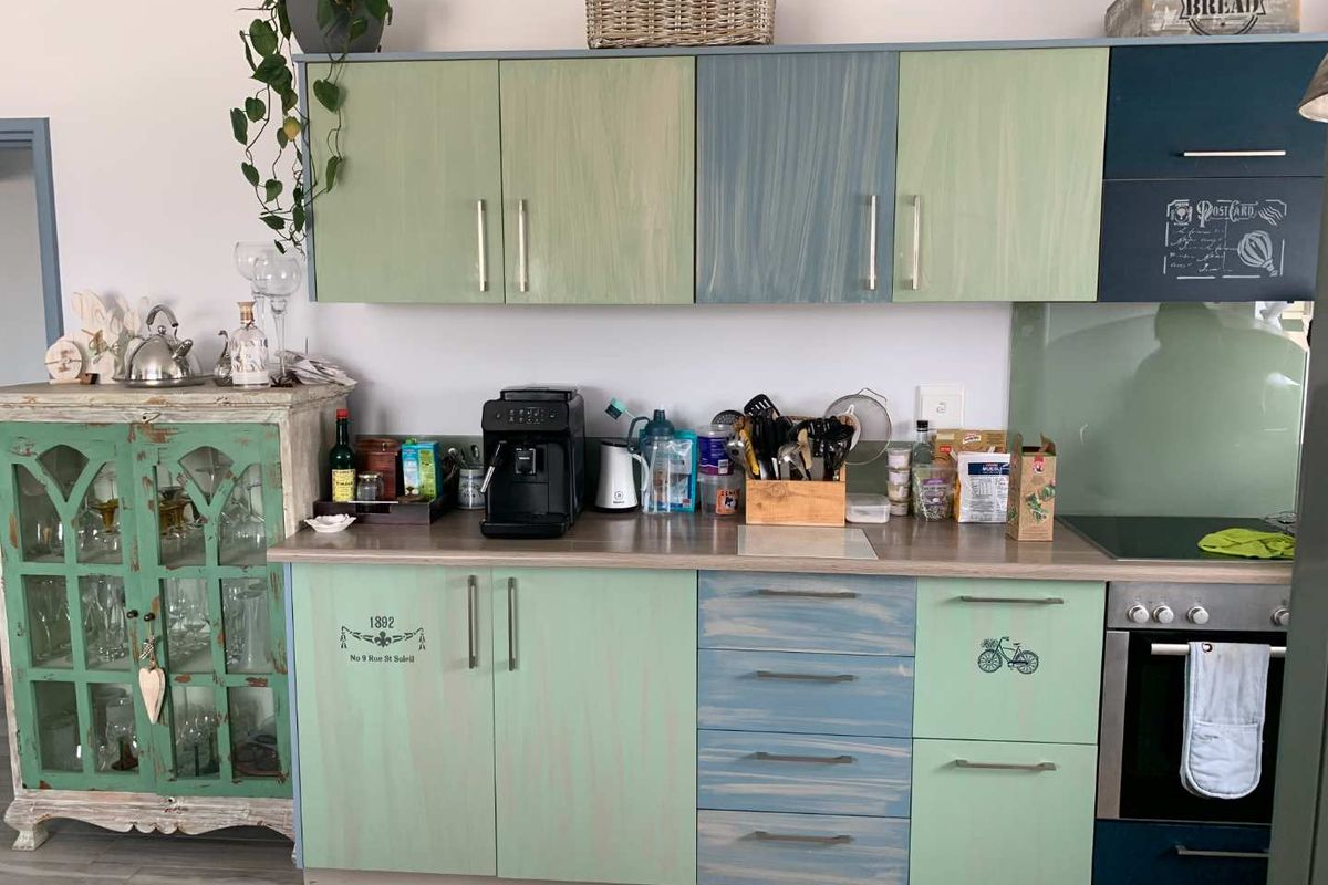 A kitchen area featuring custom-painted cabinetry, a built-in oven, and a glass splashback, offering a unique aesthetic with functional storage and workspace.
