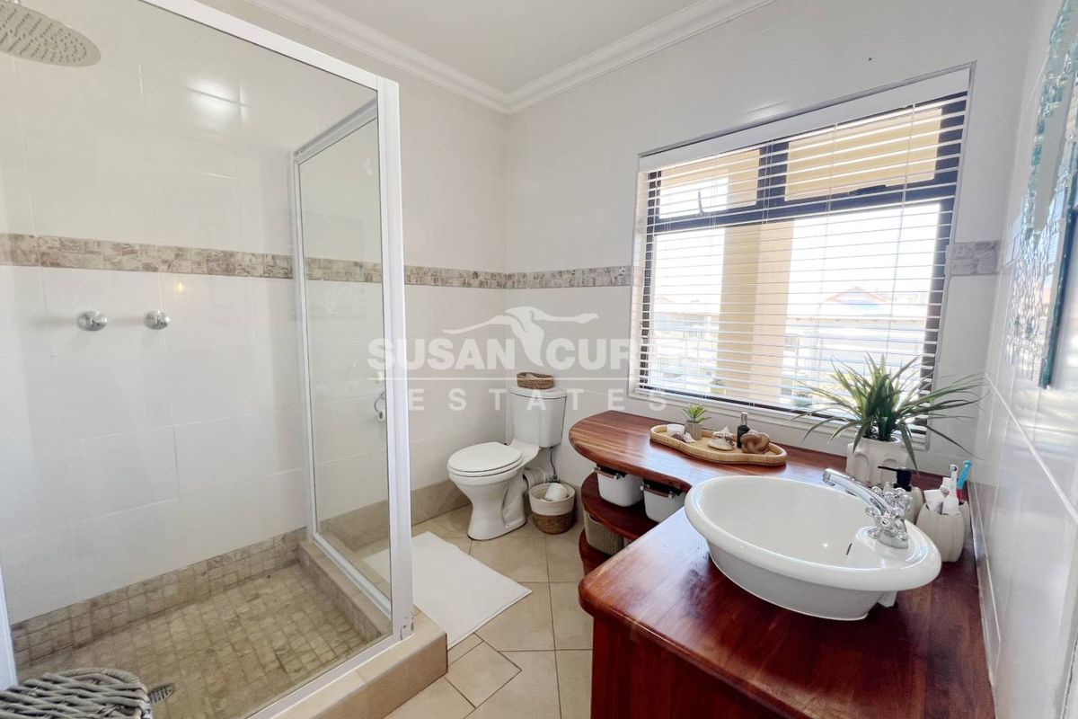 A functional bathroom featuring a glass-enclosed shower, a toilet, and a custom wooden vanity with a countertop basin.