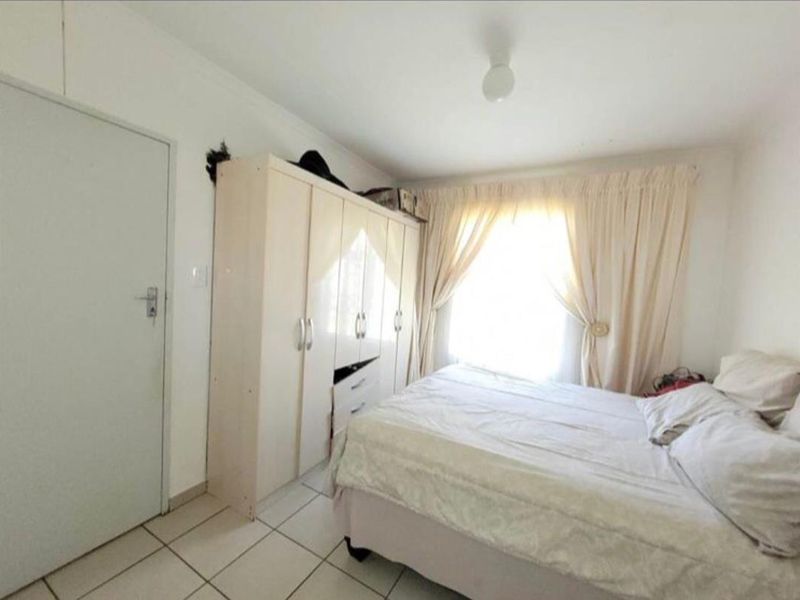 A bedroom featuring tiled flooring and a built-in wardrobe, requiring minor wall repairs to restore the finish.