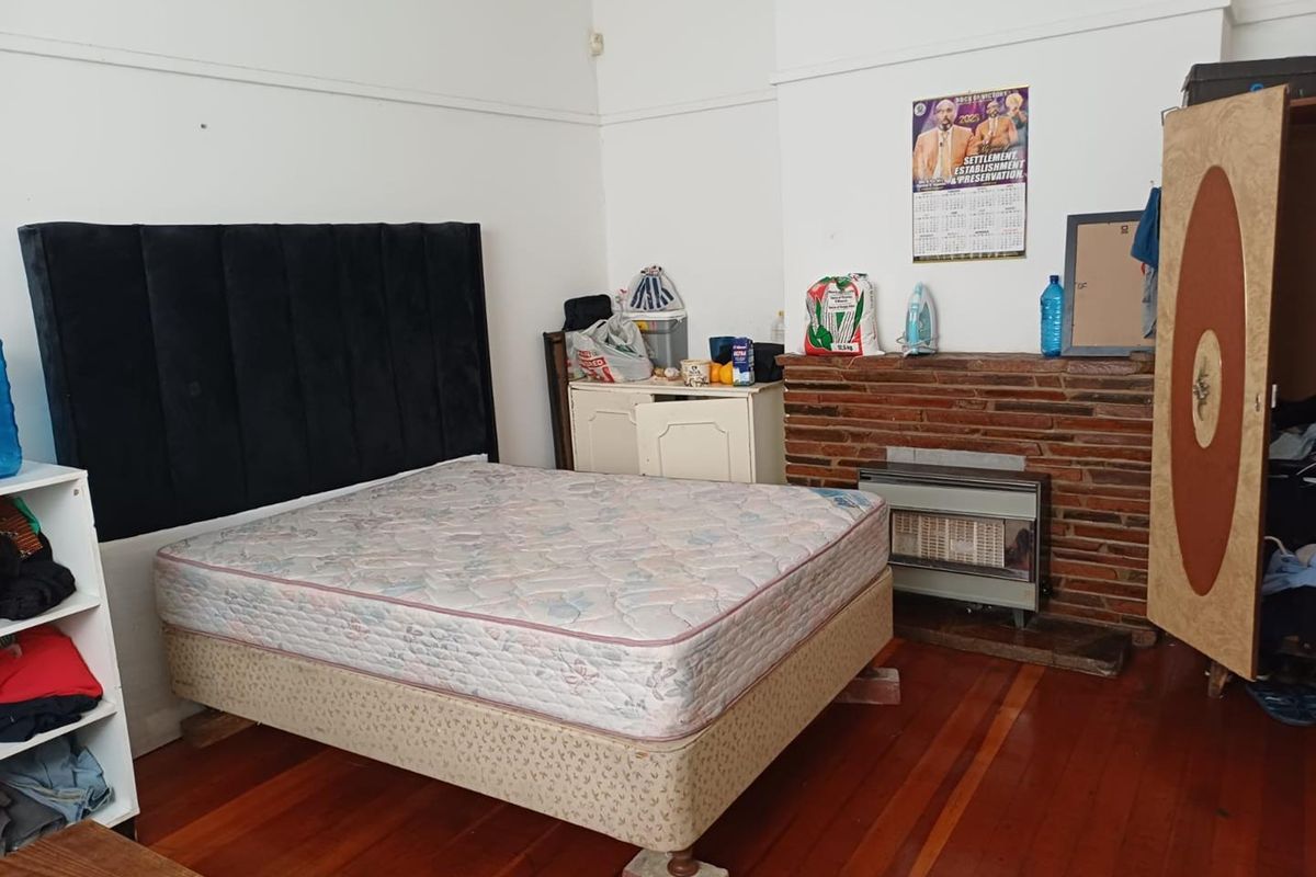 Bedroom featuring original timber flooring, a brick fireplace with an integrated gas heater, and classic picture rail detailing.