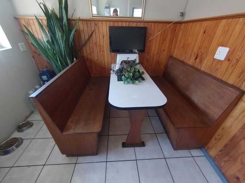 A dining area featuring built-in wooden bench seating, tiled flooring, and classic wooden wall paneling, providing a functional and compact space.