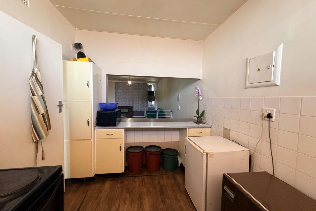 A functional kitchen area featuring built-in cabinetry, a tiled splashback, and a service hatch opening into the adjacent living space.