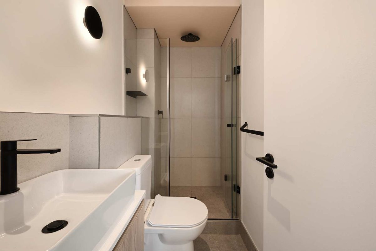 Modern bathroom featuring a walk-in shower with a rain shower head, contemporary vanity basin, and sleek matte black fixtures throughout.