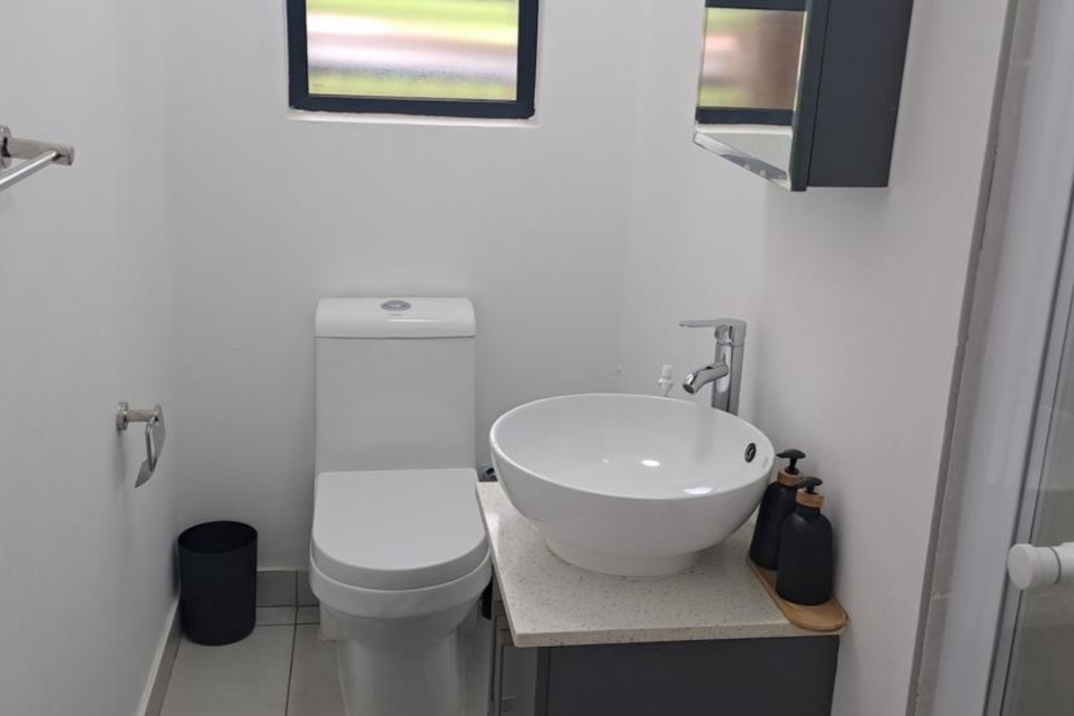 Modern bathroom featuring a contemporary vessel sink vanity, a sleek toilet, and a glass-enclosed shower area with neutral tiling.