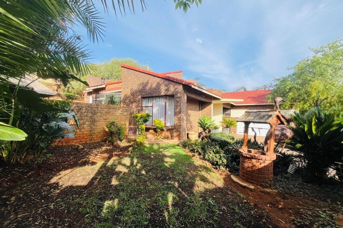 A view of the rear exterior of the house featuring face-brick walls, a tiled roof, and a landscaped garden area with a decorative well feature.