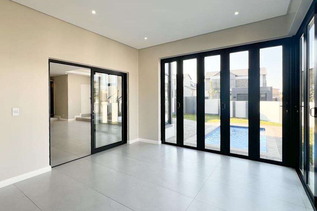 Bright and modern living area featuring large black-framed stackable doors that open directly onto the pool and garden area.