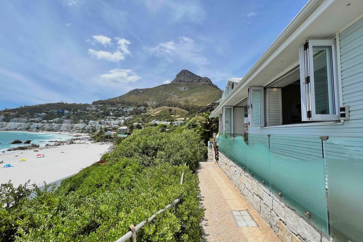 A scenic view of the coastline and mountain from the property's exterior walkway, featuring glass balustrades and bi-fold doors.
