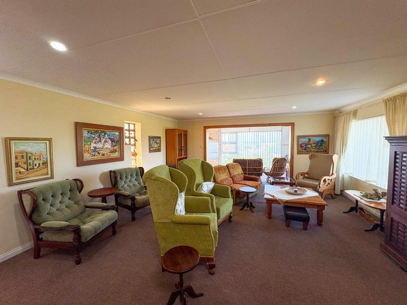 Spacious living room featuring neutral walls, carpeted flooring, recessed lighting, and large glass sliding doors leading to an outdoor area.