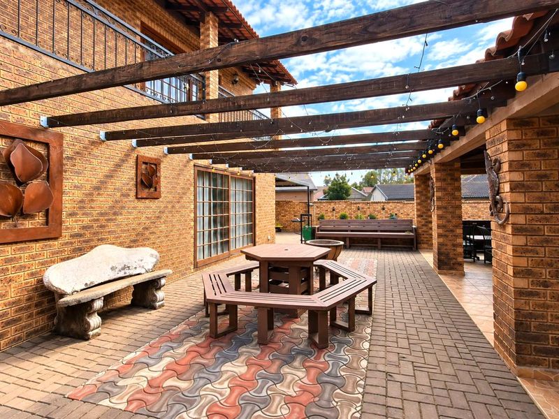 Spacious covered outdoor patio featuring a timber pergola, face brick construction, and durable paved flooring, ideal for entertaining.