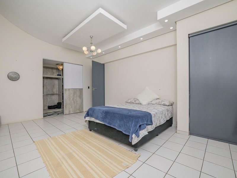 Spacious bedroom featuring a dropped ceiling with recessed lighting, tiled flooring, and a built-in wardrobe with sliding doors.