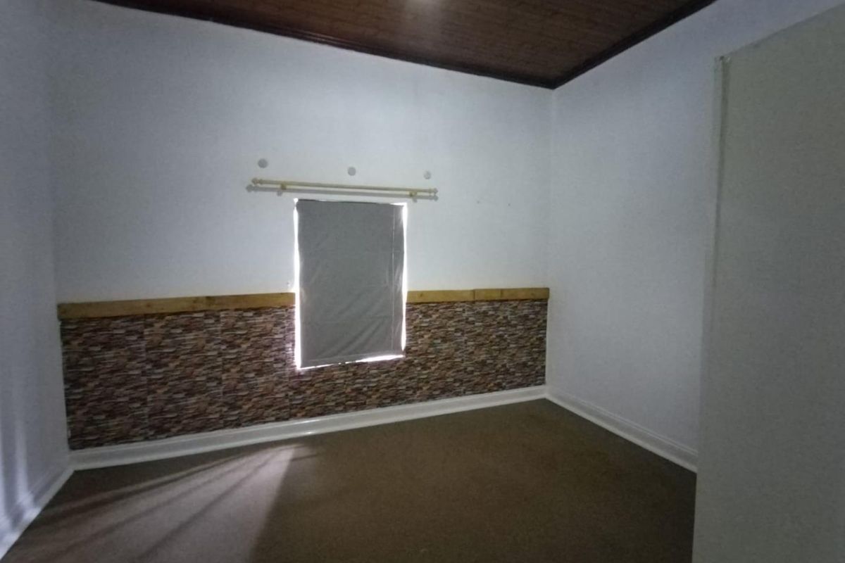 An empty bedroom featuring a timber ceiling, stone-effect wall cladding, and carpet flooring.