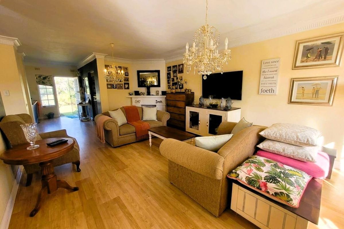 Spacious living room featuring light wood-look flooring, crown molding, and a decorative fireplace, with direct access to an outdoor patio area.