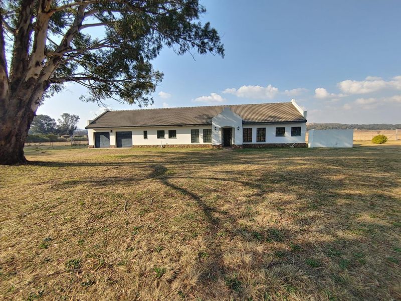 A single-story farm residence featuring a gabled entrance, tiled roof, and integrated double garage, set on a spacious rural property.