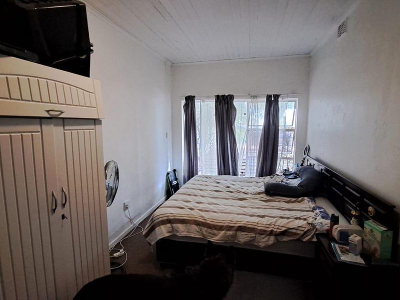 A bedroom featuring a timber ceiling and a large window, requiring cosmetic updates to improve the overall condition and appeal of the space.