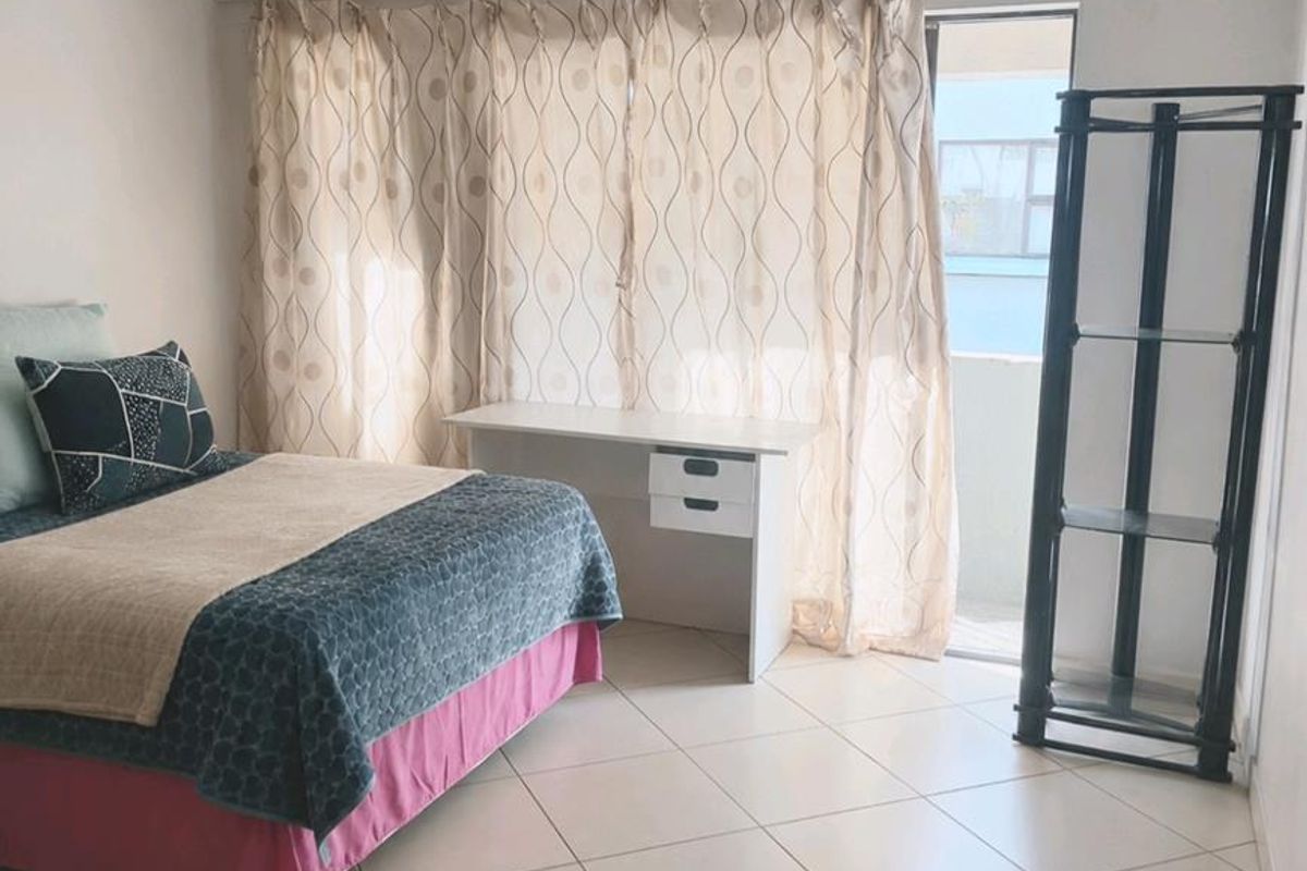A bedroom featuring tiled flooring and direct access to a balcony through a sliding glass door.