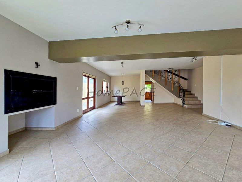 Spacious open-plan living area featuring tiled floors, a built-in fireplace, and a staircase with decorative wrought iron railing.