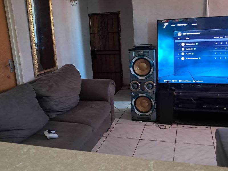 Living room area featuring tiled flooring and decorative ceiling tiles, requiring cosmetic updates to improve the overall aesthetic and finish.