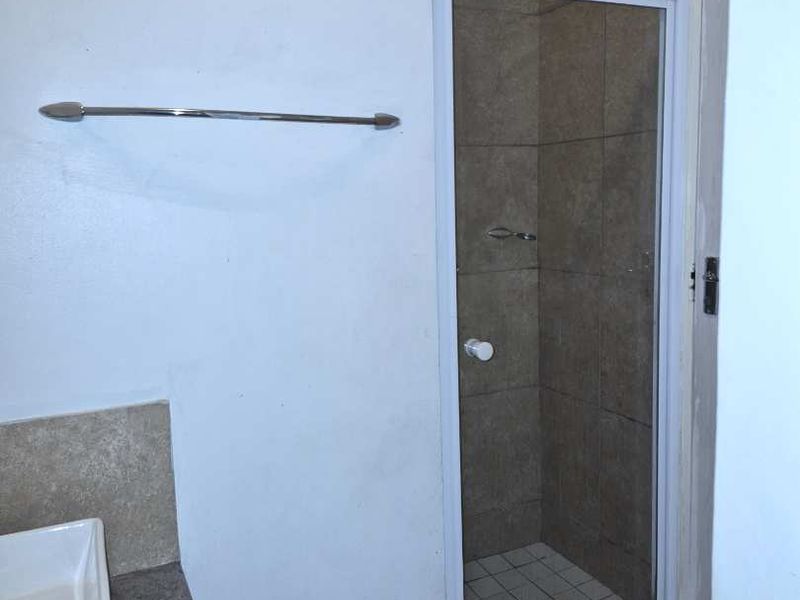 A functional bathroom featuring a tiled shower enclosure, vessel sink on a vanity countertop, and a wall-mounted towel rail.