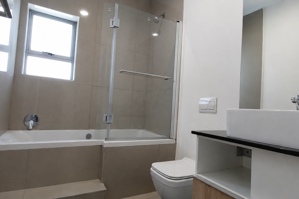 Modern bathroom featuring a built-in bathtub with glass screen, wall-mounted toilet, and a contemporary vessel sink set on a vanity cabinet.