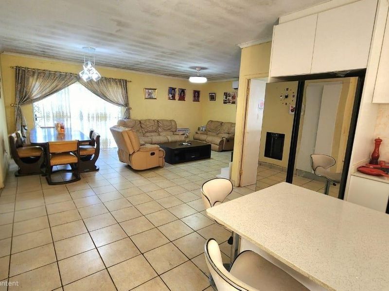 Open-plan living, dining, and kitchen area featuring tiled flooring, built-in cabinetry, and access to a patio through sliding glass doors.