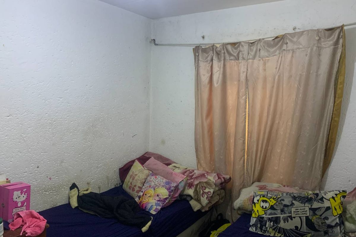A bedroom featuring textured walls with visible wear and staining, equipped with a curtain rail. The space requires cosmetic refurbishment and wall repairs.